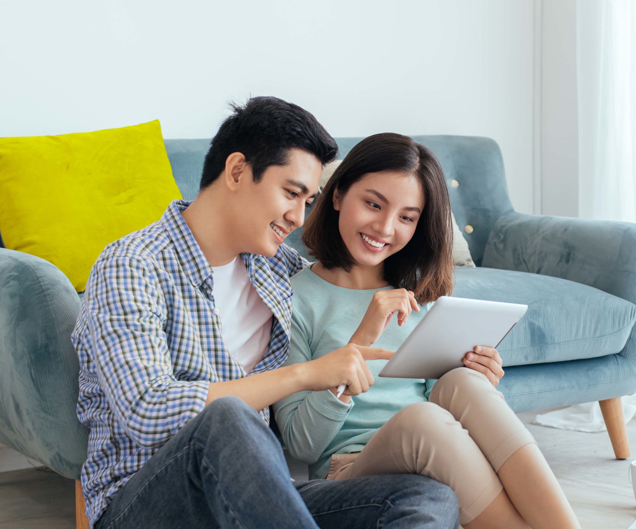 Couple in living room looking at loan options on a tablet