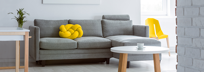 A grey couch with yellow pillows
