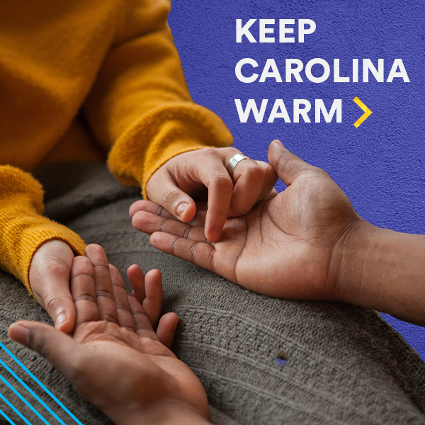 Hands touching on blanket with inset text 'KEEP CAROLINA WARM'