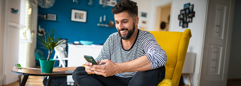 Smiling man looking at phone in living room