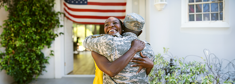 Military husband hugging wife outside home