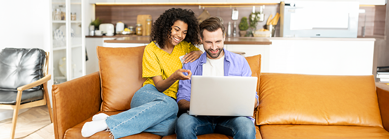 Smiling couple looking at laptop on couch